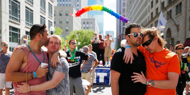 BOSTON - JUNE 12: From left, Chris Hemming, of NYC, kisses Tristan Davison, also of NYC, as Jeffery Greamo, of Boston, embraces his partner Jon Paul, also of Boston during a moment of silence held for the victims of a mass shooting at a gay night club in Florida at the Back Bay Block Party part of Boston Pride Month in Boston on June 12, 2016. (Photo by Jessica Rinaldi/The Boston Globe via Getty Images)