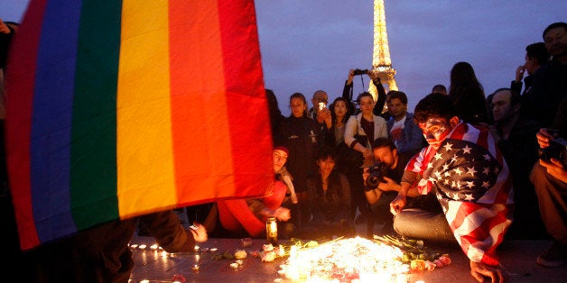 PARIS, FRANCE - JUNE 13: A man draped with the flag of the United States near candles attends a vigil in front of the Eiffel Tower for victims of a shooting inside a gay nightclub in Orlando, Florida on June 13, 2016 in Paris, France. Forty-nine people were killed and at least as many injured during a Latin music event at the Pulse club in the deadliest mass shooting in the United States. The American-born gunman Omar Mateen, who had recently pledged allegiance to ISIS, died after killing 49 people early morning on June 12. The massacre was the deadliest mass shooting in the United States. (Photo by Chesnot/Getty Images)