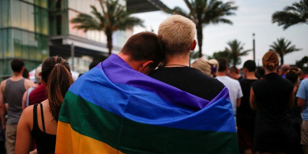 Men, draped in a rainbow flag, embrace ahead of a candle light vigil in memory of victims one day after a mass shooting at the Pulse gay night club in Orlando, Florida, U.S., June 13, 2016. REUTERS/Adrees Latif