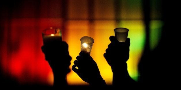 People hold up candles against a rainbow lit backdrop during a vigil for those killed in a mass shooting at the Pulse nightcl
