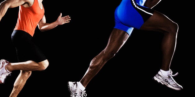 Two runners on race track with one jumping up in air