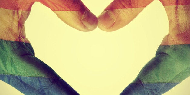 picture of man hands forming a hear patterned with the gay pride flag, with a retro effect