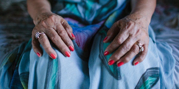 Close up of hands of older woman resting on knees