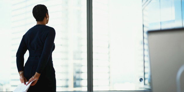 Businesswoman looking out of office window, rear view