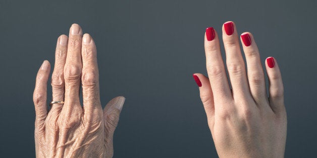 Studio photograph of elderly woman's hand beside a younger woman's hand.
