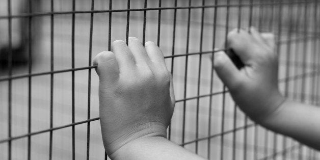 Hand of prisoner grabbed the metal fence in black and white