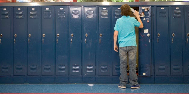 Teenage boy (13-15) putting books in locker, rear view