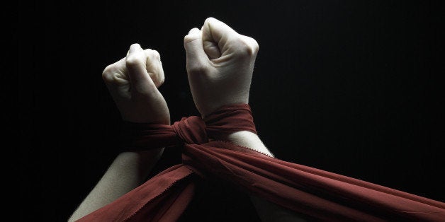 Young woman raising tied hands upwards, rear view