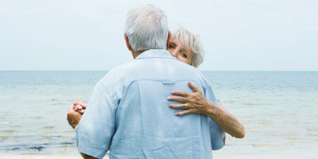 Senior couple dancing on sidewalk overlooking ocean, waist up