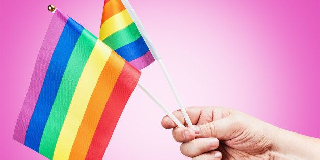 flags of the LGBT community in a hand on a purple background