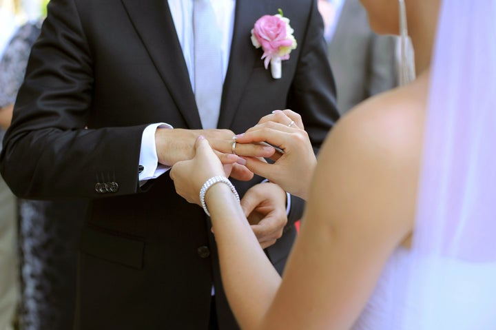 bride puts wedding ring on...