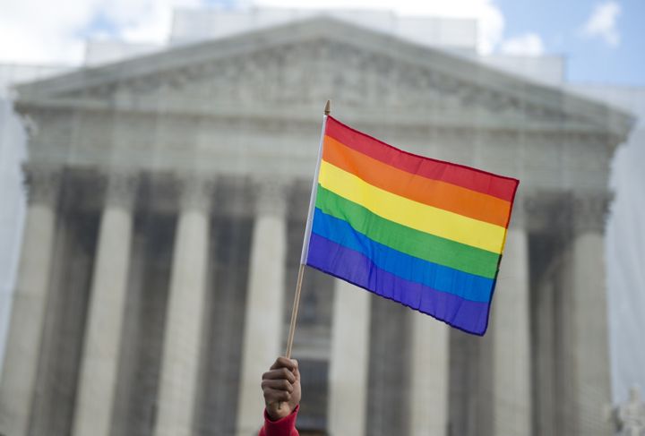 A same-sex marriage supporter waves a rainbow flag in front of the US Supreme Court on March 26, 2013 in Washington, DC, as the Court takes up the issue of gay marriage. The US Supreme Court on Tuesday heard arguments on the emotionally charged issue of gay marriage as it considers arguments that it should make history and extend equal rights to same-sex couples. Waving US and rainbow flags, hundreds of gay marriage supporters braved the cold to rally outside the court along with a smaller group of opponents, some pushing strollers. Some slept outside in hopes of witnessing the historic hearing. AFP PHOTO / Saul LOEB (Photo credit should read SAUL LOEB/AFP/Getty Images)