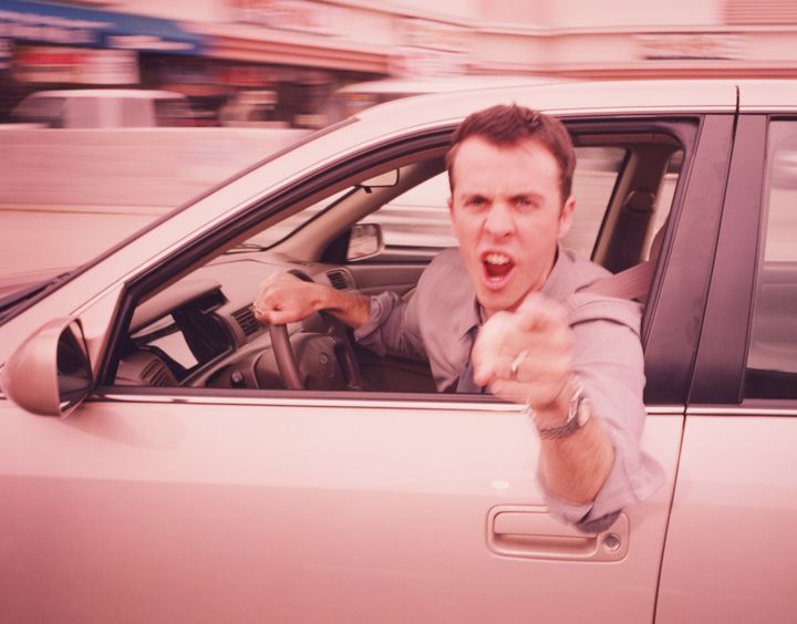 Man driving, leaning out of car, pointing angrily (blurred motion)