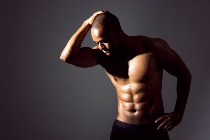 Young black man flexing abs. Dramatic lighting.