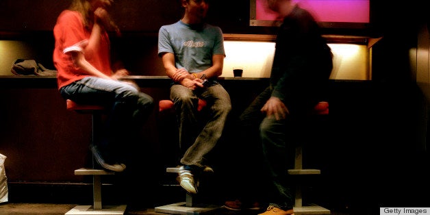 Three men sitting on bar stools in Freedom Cafe., Soho, London, London, England.