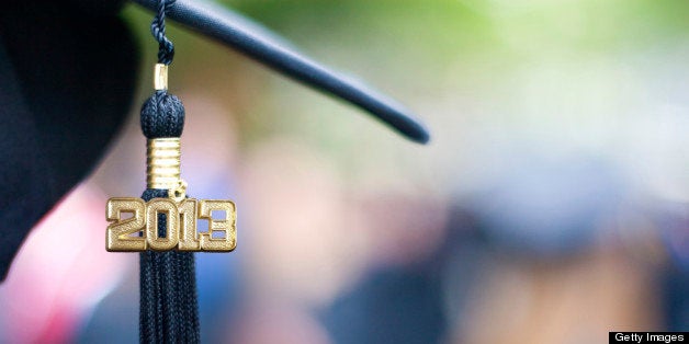 Graduation cap and tassel with 2013 for Class of 2013. Blurred out graduates in background.