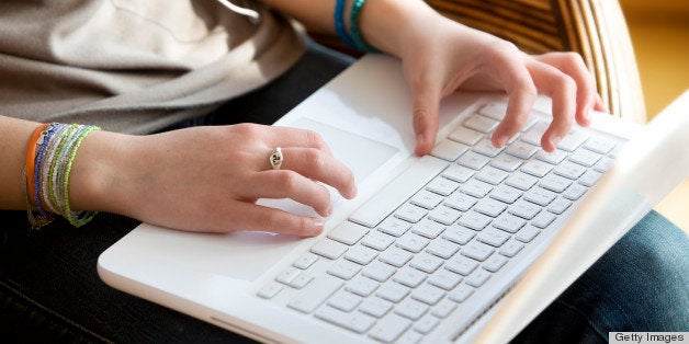 Close-up on teenager's hands typing on laptop's keyboard.