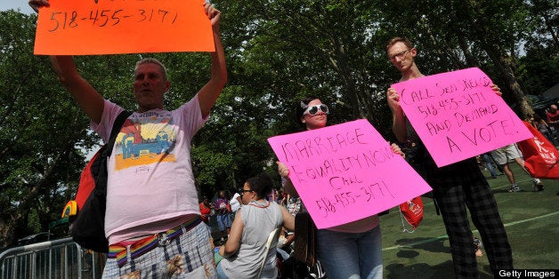 Ted McGuire (L), Amanda Rose (C) and Eugene Lovendusky (R) from the advocacy group Queer Rising hold signs supporting same-sex marriage at the NYC Lesbian, Gay, Bisexual and Transgender Pride Rally June 18, 2011 in New York's Central Park, kicking off the annual gay and lesbian Pride Week. New York state is considering legislation to become the sixth state in the country to legalize same-sex marriage. AFP PHOTO/Stan HONDA (Photo credit should read STAN HONDA/AFP/Getty Images)