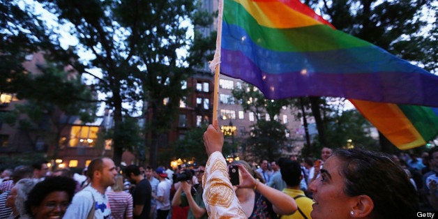 NEW YORK, NY - JUNE 26: A woman waves a rainbow flag after the Supreme Court ruled key portions of the Defense of Marriage A