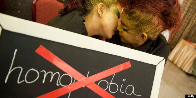 A lesbian couple kisses behind a placard reading 'Homophobia' as they take part in an event to celebrate the International day against Homophobia and Transphobia on May 17, 2013, in Yangon. AFP PHOTO / YE AUNG THU (Photo credit should read Ye Aung Thu/AFP/Getty Images)
