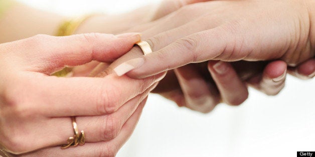 Woman's hand putting wedding ring on her female partner's hand in a wedding ceremony