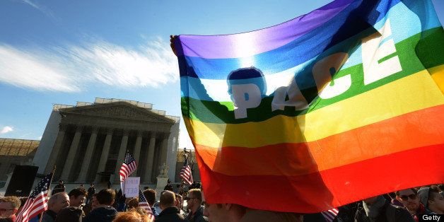 WASHINGTON, DC - MARCH 27: GW student Cam Tucker is silhouetted behind a rainbow flag in front of the Supreme Court where arguments are being heard in a case against the Defense of Marriage Act on March, 27, 2013 in Washington, DC. The flag says PACE, which is Italian for Peace, according to Tucker. (Photo by Bill O'Leary/The Washington Post via Getty Images)