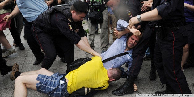 Police officers separate an orthodox activist (back) and gay rights activist (front) clashing just outside the lower house of