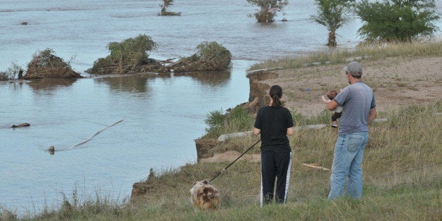 EVANS, CO - SEPTEMBER 17: Family members look over a flooded field September 17, 2013 near Evans, in eastern Colorado. Even as flooding subsides, many in the hardest hit areas of the state remain stranded by washed out roads and rushing creeks and without water and power. (Photo by Thomas Cooper/Getty Images)