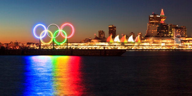 The Olympic Rings light up Coal Harbor/Harbour in front of Canada Place and downtown Vancouver at dawn. Vancouver British Columbia Canada.