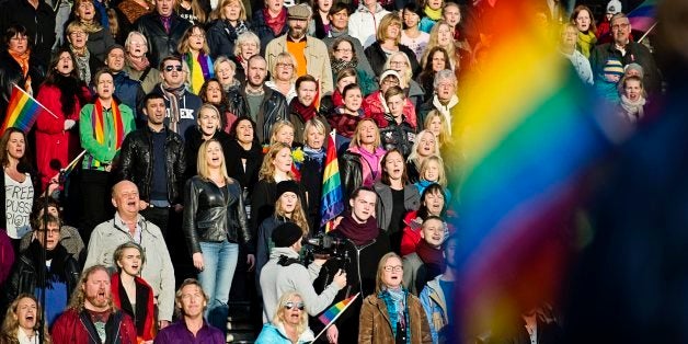 A crowd of people sing the Russian National Anthem at the Stockholm Olympic Stadium on October 6, 2013 while raising rainbow
