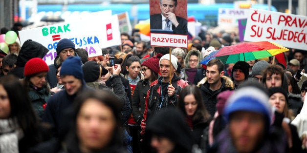 Croatian gay rights supporters hold a picture of Tomislav Karamarko, leader of the conservative opposition Croatian Democratic Union party, reading 'Divorced' as they gather for a protest in Zagreb on November 30, 2013 on the eve of a constitutional referendum that could outlaw same-sex marriage in the EU's newest member state. More than 1,000 people braved the cold and rainy weather to gather in a square in conservative and mainly Catholic Croatia for a protest march against the vote, which they see as discriminatory. AFP PHOTO/STR (Photo credit should read STR/AFP/Getty Images)