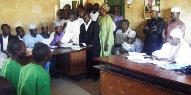 A picture taken on January 22, 2014 shows two suspected homosexuals in green prison uniforms (L) sitting before Judge El-Yakubu Aliyu during court proceedings at Unguwar Jaki Upper Sharia Court in the northern Nigerian city of Bauchi. Two Islamic courts in northern Nigeria have been forced to suspend the trials of 10 men accused of homosexuality because of fears of mob violence, judges and officials have said on January 29. An angry crowd last week pelted stones at seven men suspected of breaking Islamic law banning homosexuality after their hearing was adjourned at the Unguwar Jaki Upper Sharia Court in Bauchi. AFP PHOTO / AMINU ABUBAKAR (Photo credit should read AMINU ABUBAKAR/AFP/Getty Images)