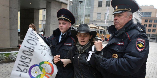 Police officers detain a gay rights activist during an unauthorized protest against hotly disputed Russian laws banning the promotion or display of homosexuality in front of minors outside the headquarters of the Sochi 2014 Organizing Committee in central Moscow on September 25, 2013. The partly seen poster reads: 'Homophobia is the shame of Russia!' The law on gay 'propaganda', which was signed by President Vladimir Putin earlier this year, has prompted calls for a boycott of Sochi or for the Games to be moved outside Russia. AFP PHOTO / ALEXANDER NEMENOV (Photo credit should read ALEXANDER NEMENOV/AFP/Getty Images)