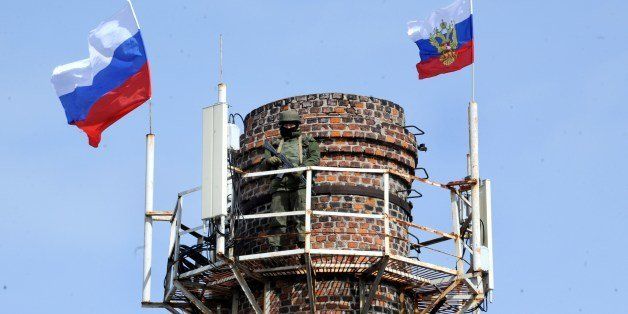 A Russian soldier patrols on a chimney with Russian flags at the Ukrainian navy headquarters in the Crimean city of Sevastopol on March 19, 2014. Pro-Russian forces captured Ukraine's naval commander after seizing his headquarters in Crimea on Wednesday as Moscow's grip tightened on the peninsula despite Western warnings its 'annexation' would not go unpunished. AFP PHOTO/ VIKTOR DRACHEV (Photo credit should read VIKTOR DRACHEV/AFP/Getty Images)