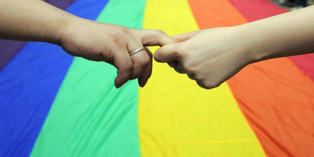 Gay and lesbian activists form a human chain around a rainbow flag during celebrations marking the fourth annual International Day Against Homophobia (IDAHO) in Hong Kong on May 18, 2008. The International Day Against Homophobia, marked in most places around the world on May 17, was launched in 2005 to commemorate the day in 1990 when the World Health Organisation removed homosexuality from its list of disorders. AFP PHTO/TED ALJIBE (Photo credit should read TED ALJIBE/AFP/Getty Images)