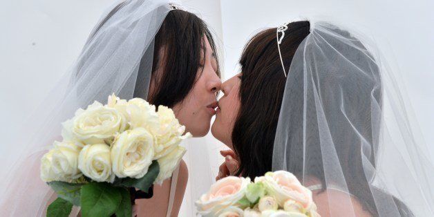 A lesbian couple kisses as they pose for photos taken by a wedding photo service company in Tokyo before participating in the 'Tokyo Rainbow Pride' parade in Tokyo on April 27, 2014. Some 3,000 supporters of the lesbian, gay, bisexual and transgender community (LGBT), many in costume, marched in Tokyo's Shibuya and Harajuku shopping districts. AFP PHOTO / Yoshikazu TSUNO (Photo credit should read YOSHIKAZU TSUNO/AFP/Getty Images)