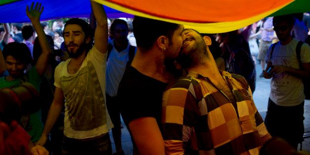 ISTANBUL, TURKEY - JUNE 23: A couple embrace under a rainbow flag as they attend a march down Istiklal Street to kick off Gay Pride Week in Istanbul, Turkey on June 23, 2013. The yearly parade comes in the midst of political turmoil, with many in the LGBT community claiming that their freedoms are slowly eroding in the face of Prime Minister Recep Tayyip Erdogan and the AK Party's Islamic minded policies slowly creeping into secular life. The parade saw chants for both LGBT rights, and also echoed the same chants of the anti-government protests which have rocked the country in the last month. (Ed Ou/Getty Images)