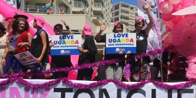 People stand on a float holding signs saying 'Love Uganda, hate homophobia' in reaction to Uganda's law banning homosexuality. Hundreds of people gathered on the streets of Green Point in Cape Town, South Africa, on March 1, 2014 to take part in the 2014 Gay Pride Parade. AFP PHOTO/JENNIFER BRUCE (Photo credit should read JENNIFER BRUCE/AFP/Getty Images)