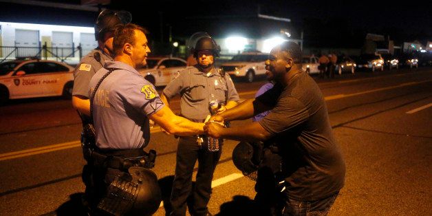 A man walks up and greets police officers during nighttime demonstrations in Ferguson, Missouri, U.S., on Tuesday, Aug. 19, 2014. A grand jury will begin hearing evidence tomorrow in the police shooting death of Ferguson, Missouri, teenager Michael Brown, as violent clashes continued in the St. Louis suburb. Photographer: Luke Sharrett/Bloomberg via Getty Images