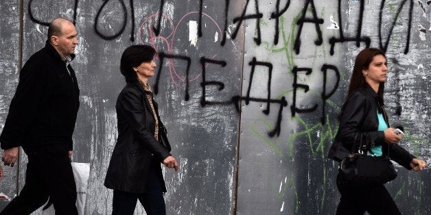 Pedestrian walk past a anti-gay graffiti, reading 'Stop the parade of fags', in Belgrade on September 26, 2014. Belgrade will