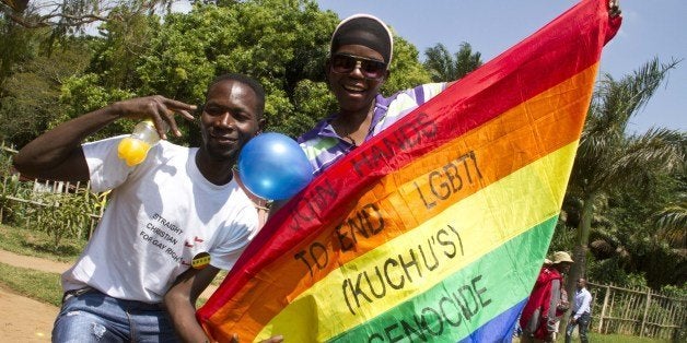 Ugandan men hold a rainbow flag reading 'Join hands to end LGBTI (Lesbian Gay Bi Trans Intersex - called Kuchu in Uganda) genocide' as they celebrate on August 9, 2014 during the annual gay pride in Entebbe, Uganda. Uganda's attorney general has filed an appeal against the constitutional court's decision to overturn tough new anti-gay laws, his deputy said on August 9. Branded draconian and 'abominable' by rights groups but popular domestically, the six-month old law which ruled that homosexuals would be jailed for life was scrapped on a technicality by the constitutional court on August 1. AFP PHOTO/ ISAAC KASAMANI (Photo credit should read ISAAC KASAMANI/AFP/Getty Images)