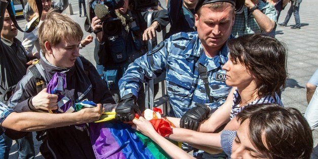 A man (L) takes away a rainbow flag as a policeman detain gay rights activists during their protest in central Moscow on May
