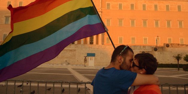 ATHENS, GREECE - 2014/06/14: A gay couple kiss in front of the Greek parliament building whilst holding a Rainbow colored flag. Hundreds of people on Saturday joined Greece's annual gay pride parade in a long-standing demand for equal rights to civil union and adoption. (Photo by George Panagakis/Pacific Press/LightRocket via Getty Images)