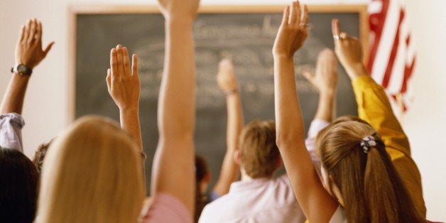 Students raising hands in classroom, rear view