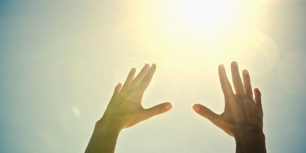 Mixed race woman's hands reaching toward sun