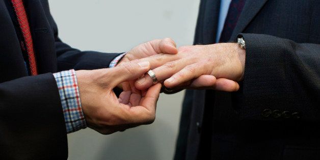 Man putting wedding ring on another man's finger