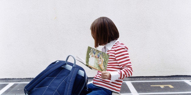 Girl (5-7) looking at book in playground