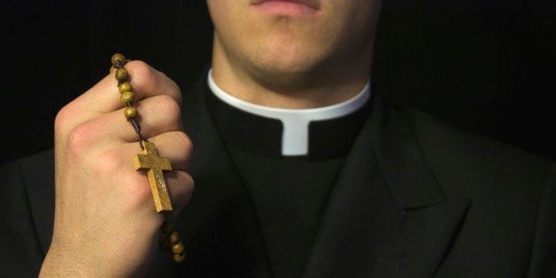 Young Priest praying with rosery in his hands