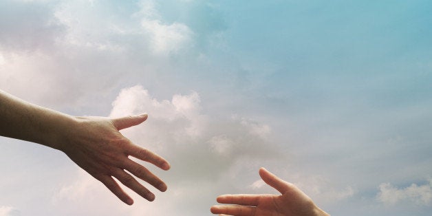 Hand of father and daughter seem to reach together in the sky