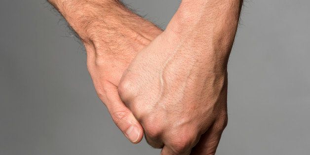 Two gay men holding hands on gray background